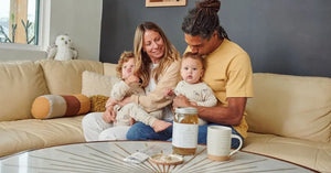 Family sitting together on a cozy couch with Bone Broth Elixir and a ceramic mug on the table nearby