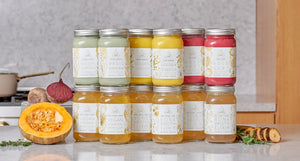 OWL Reset Cleanse jars labeled with organic ingredients like Magic Matcha and Bold Beet, displayed alongside fresh pumpkin, beets, and herbs