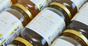 Organic bone broth jars labeled "Bone Broth Elixir" with golden accents, featuring flavors like beef and fennel.