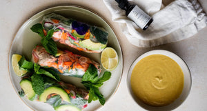 Salmon Avocado Fresh Rolls on a plate with vibrant greens, avocado slices, and edible flowers, served with a bowl of dipping sauce and OWL’s Yeast Buster herbal supplement