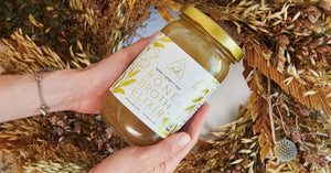 Hands holding a jar of bone broth cleanse surrounded by autumnal decorations