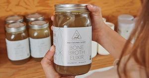 Bone broth detox featuring a jar of bison and turmeric bone broth elixir held in front of a wooden shelf